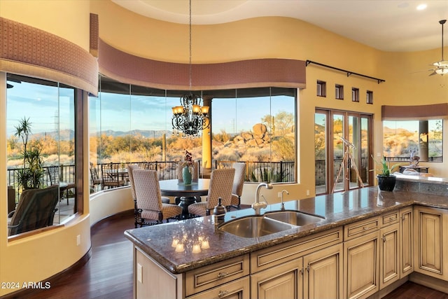 kitchen featuring a mountain view, dark stone counters, ceiling fan with notable chandelier, sink, and decorative light fixtures