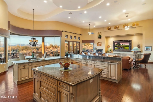 kitchen with ceiling fan, sink, decorative light fixtures, a high ceiling, and a center island