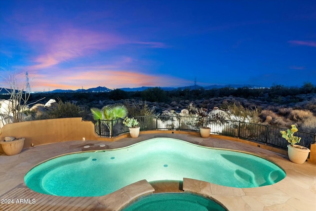 pool at dusk with an in ground hot tub and a mountain view