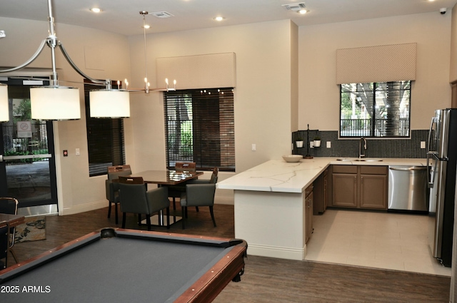 kitchen with kitchen peninsula, pendant lighting, stainless steel appliances, and pool table