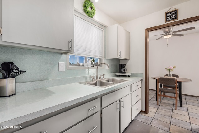 kitchen featuring decorative backsplash, white cabinets, ceiling fan, light tile patterned flooring, and sink