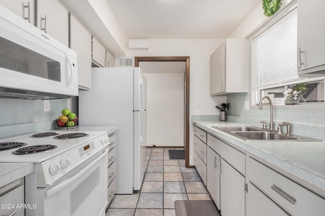 kitchen featuring white appliances, light tile patterned floors, white cabinetry, and sink