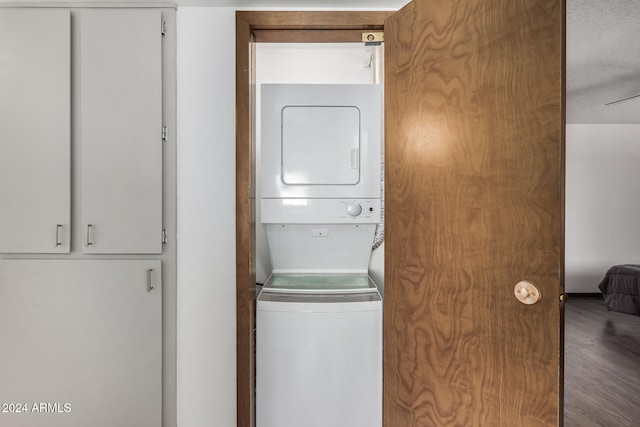 laundry area with a textured ceiling, stacked washer / drying machine, wood-type flooring, and ceiling fan