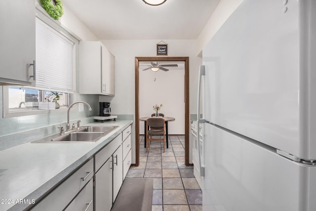 kitchen with white cabinets, ceiling fan, light tile patterned flooring, sink, and white refrigerator