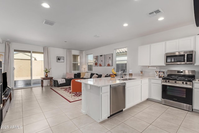 kitchen with kitchen peninsula, appliances with stainless steel finishes, white cabinetry, and sink