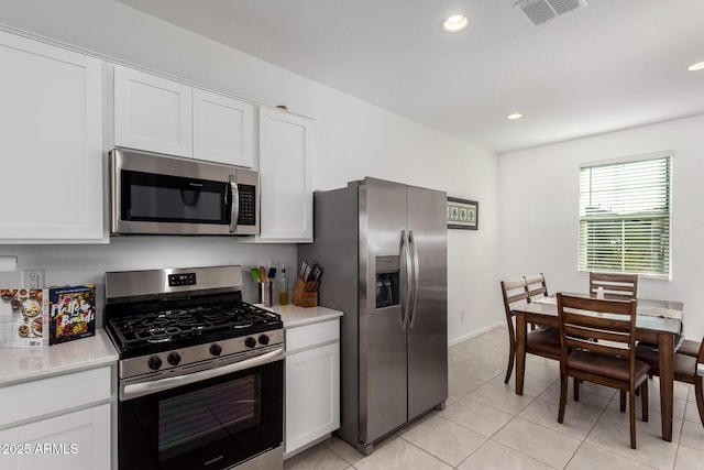 kitchen with white cabinets, light tile patterned floors, and stainless steel appliances