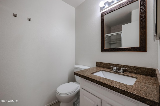 bathroom with vanity, a shower with door, and toilet