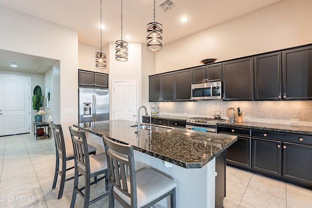 kitchen featuring visible vents, decorative backsplash, a high ceiling, stainless steel appliances, and a sink