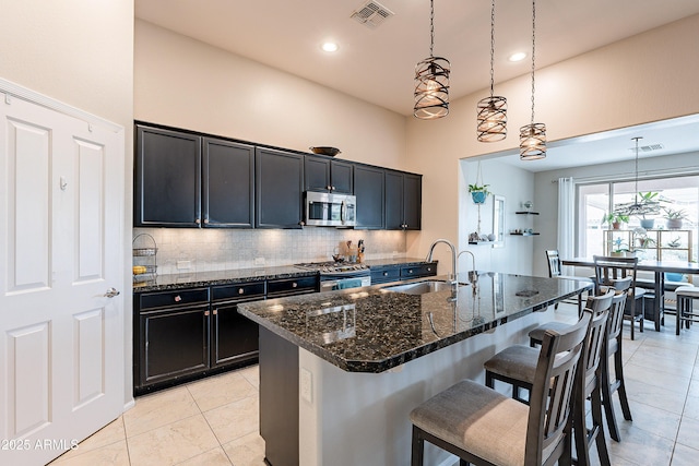 kitchen with visible vents, decorative backsplash, dark stone countertops, stainless steel appliances, and a sink