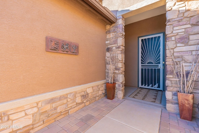 view of exterior entry with stone siding and stucco siding