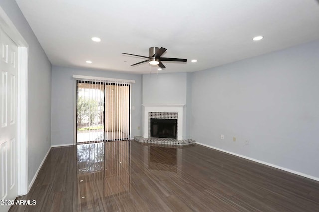 unfurnished living room featuring wood finished floors, a brick fireplace, a ceiling fan, and baseboards