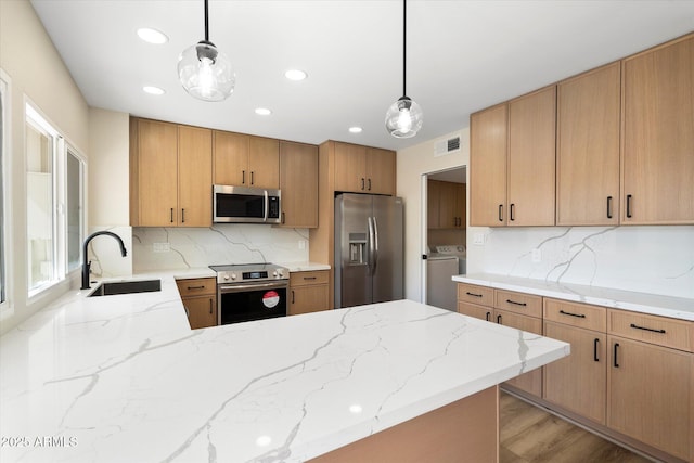 kitchen with visible vents, light stone countertops, a peninsula, stainless steel appliances, and a sink