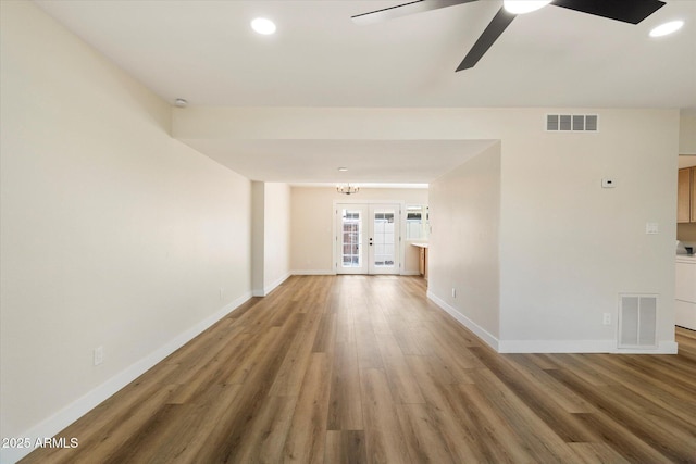 unfurnished living room featuring visible vents, baseboards, light wood-style floors, and french doors