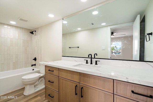 full bath with visible vents, toilet, vanity, wood finished floors, and washtub / shower combination