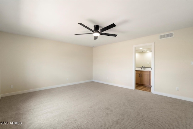 unfurnished bedroom with visible vents, connected bathroom, baseboards, ceiling fan, and light colored carpet