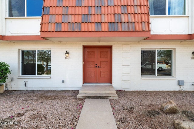 property entrance featuring brick siding and a tiled roof