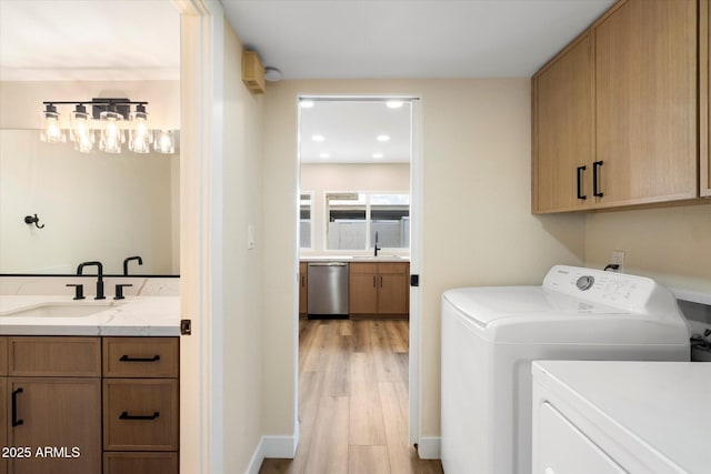 laundry area with washer and clothes dryer, cabinet space, light wood-style floors, and a sink