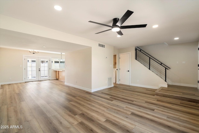 unfurnished living room featuring stairs, wood finished floors, visible vents, and baseboards