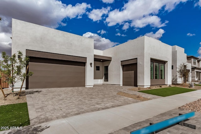 view of front of house with a garage, decorative driveway, and stucco siding