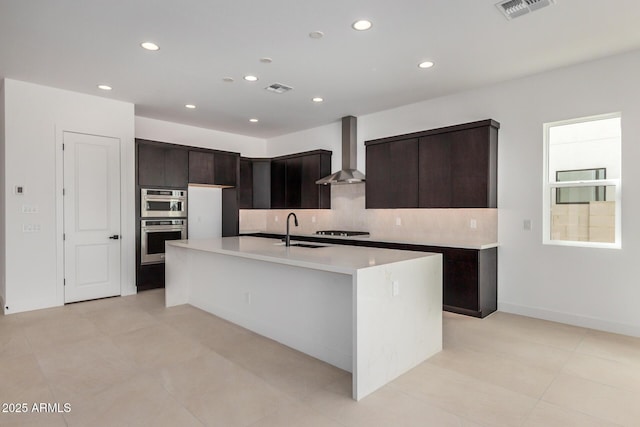 kitchen with wall chimney exhaust hood, visible vents, a sink, and stovetop