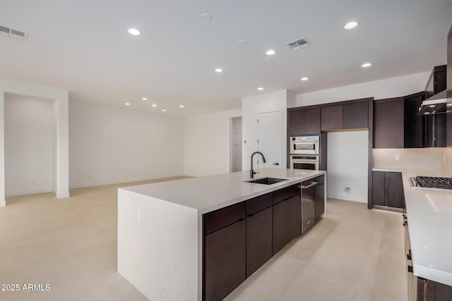 kitchen featuring dark brown cabinetry, visible vents, a kitchen island with sink, a sink, and recessed lighting