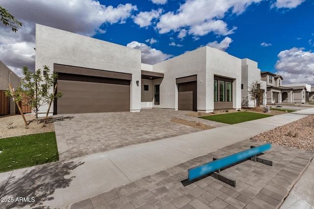 view of front of house featuring decorative driveway, an attached garage, and stucco siding