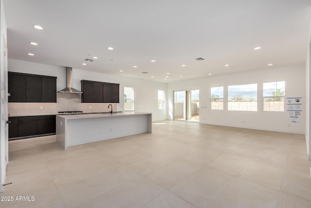 kitchen with open floor plan, light countertops, wall chimney range hood, and modern cabinets