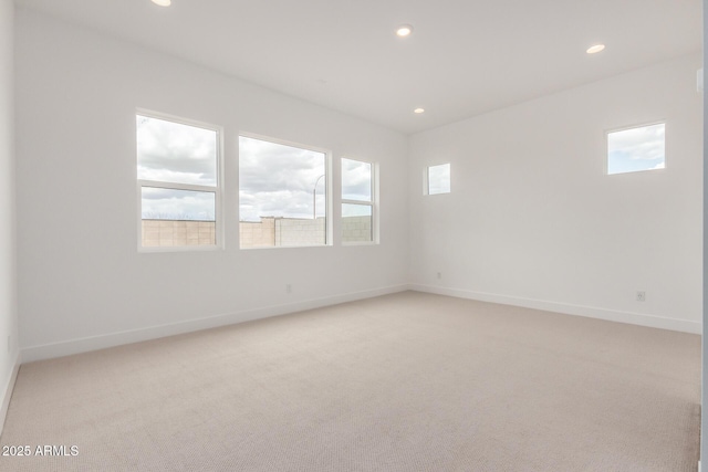 spare room featuring recessed lighting, baseboards, and light colored carpet