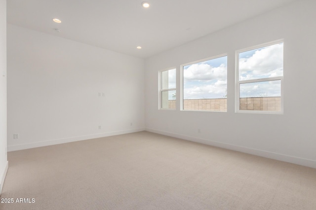 empty room featuring recessed lighting, light carpet, and baseboards