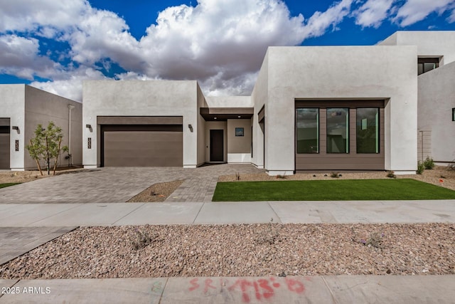 view of front of house with an attached garage, decorative driveway, and stucco siding