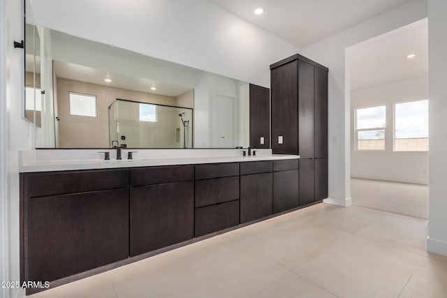 bathroom featuring a stall shower, a healthy amount of sunlight, a sink, and double vanity