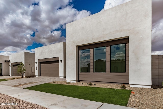 view of front of property featuring a garage, decorative driveway, and stucco siding