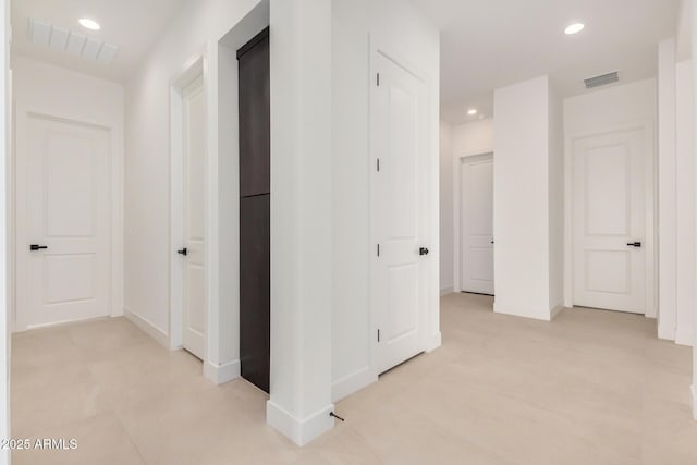 hall with baseboards, visible vents, and recessed lighting