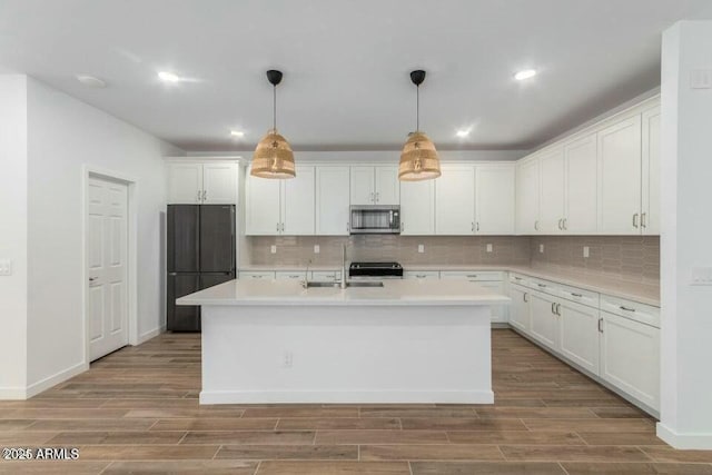 kitchen featuring decorative light fixtures, white cabinetry, and a kitchen island with sink