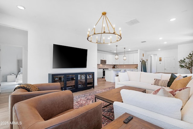 living room featuring an inviting chandelier and light wood-type flooring