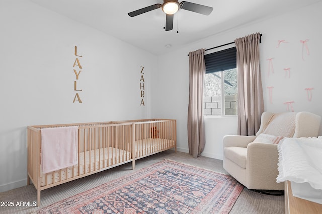 bedroom featuring ceiling fan, a crib, and carpet