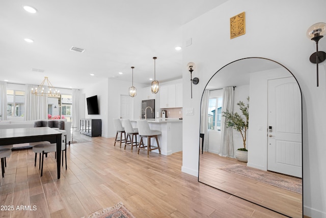 interior space with sink, an inviting chandelier, light hardwood / wood-style floors, and plenty of natural light