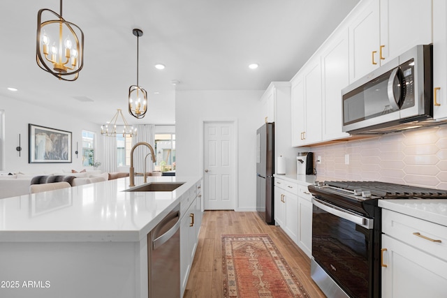 kitchen with appliances with stainless steel finishes, an island with sink, decorative light fixtures, and sink