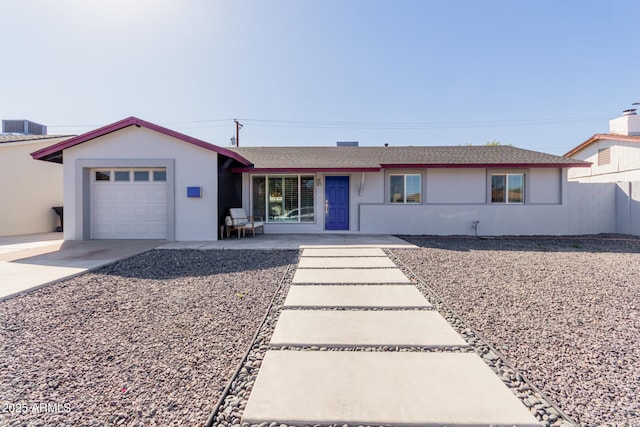 single story home with a garage, driveway, central AC, and stucco siding