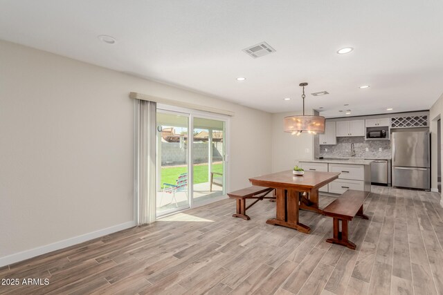 dining space featuring light wood finished floors, recessed lighting, visible vents, and baseboards