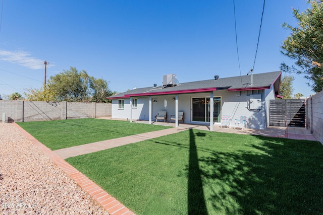 rear view of house with a patio area, a fenced backyard, and a lawn