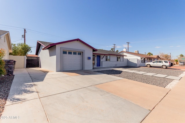 single story home with driveway, a garage, a gate, fence, and stucco siding