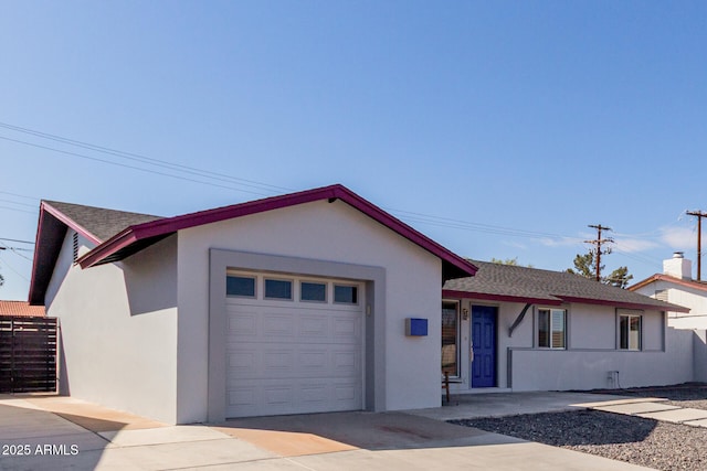 ranch-style home featuring an attached garage, fence, concrete driveway, and stucco siding