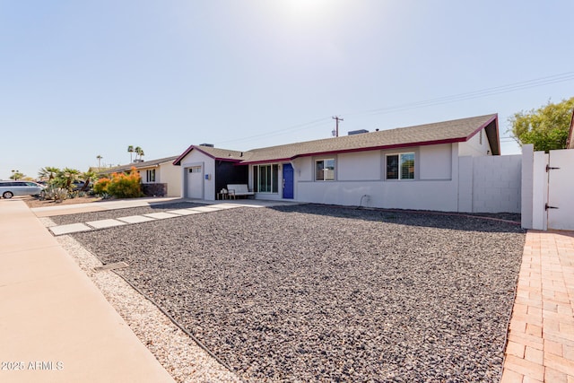 ranch-style home with stucco siding, an attached garage, a gate, fence, and driveway