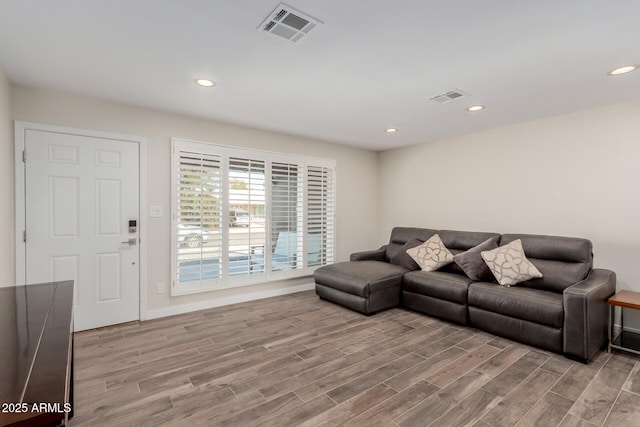 living room with light wood-style flooring, visible vents, and recessed lighting