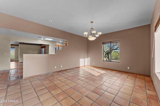 tiled empty room featuring a chandelier