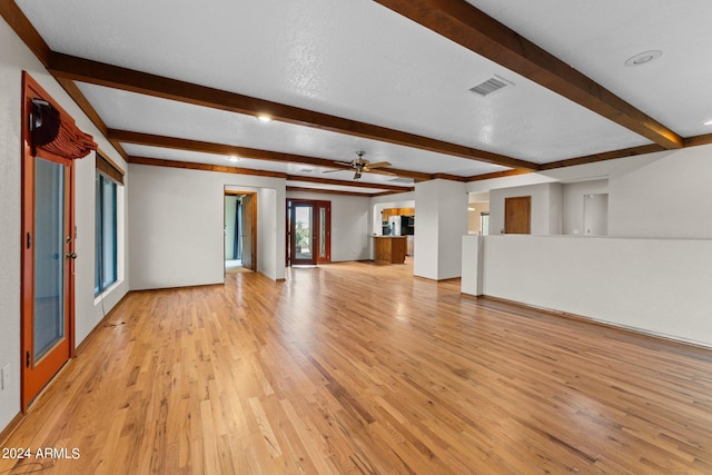 unfurnished living room with beamed ceiling, ceiling fan, light hardwood / wood-style floors, and a textured ceiling