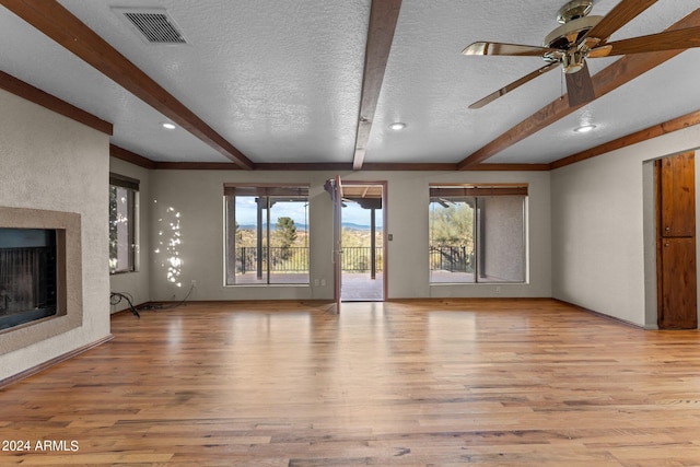 unfurnished living room with beam ceiling, light hardwood / wood-style floors, and a textured ceiling