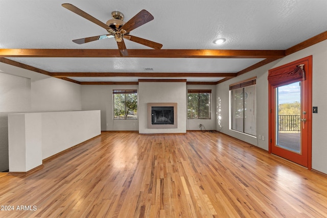 unfurnished living room featuring beam ceiling, a textured ceiling, and light hardwood / wood-style flooring