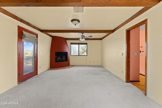 unfurnished living room featuring beamed ceiling, light colored carpet, a fireplace, and ceiling fan